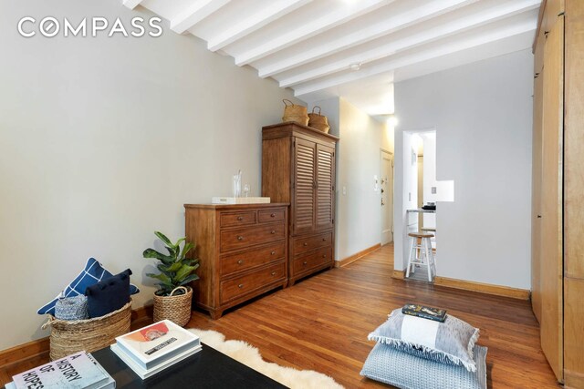 interior space with vaulted ceiling with beams, baseboards, and wood finished floors