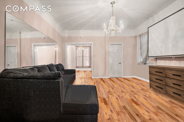 living area with light wood-style floors, a notable chandelier, and baseboards