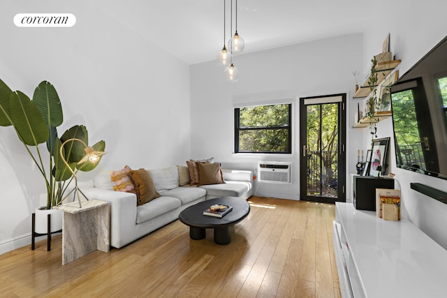 living area with a wall unit AC, light wood finished floors, and visible vents