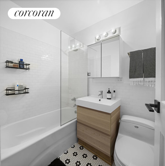 full bathroom featuring toilet, tile patterned floors, bathtub / shower combination, vanity, and tile walls