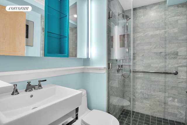 bathroom with a sink, toilet, and a shower stall