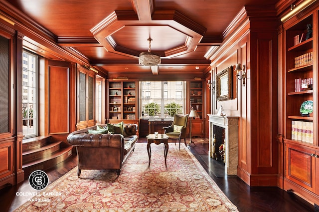 sitting room featuring ornamental molding, coffered ceiling, a high end fireplace, and built in features