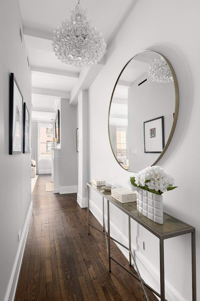 corridor featuring wood-type flooring, baseboards, and a chandelier