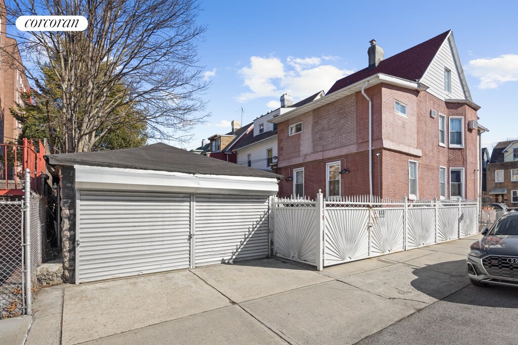 901 Newkirk Ave, New York City, NY 11230 - view of side of property featuring a chimney, fence, an outdoor structure, brick siding, and a garage