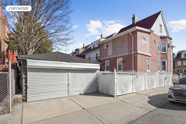 901 Newkirk Ave, New York City, NY 11230 - view of side of property featuring a chimney, fence, an outdoor structure, brick siding, and a garage