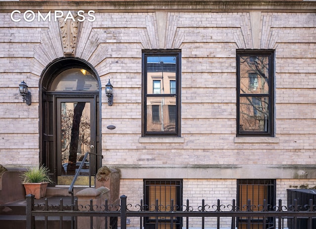 doorway to property with brick siding and fence