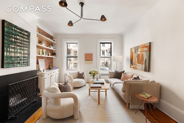 living area with light wood-type flooring, radiator heating unit, and baseboards