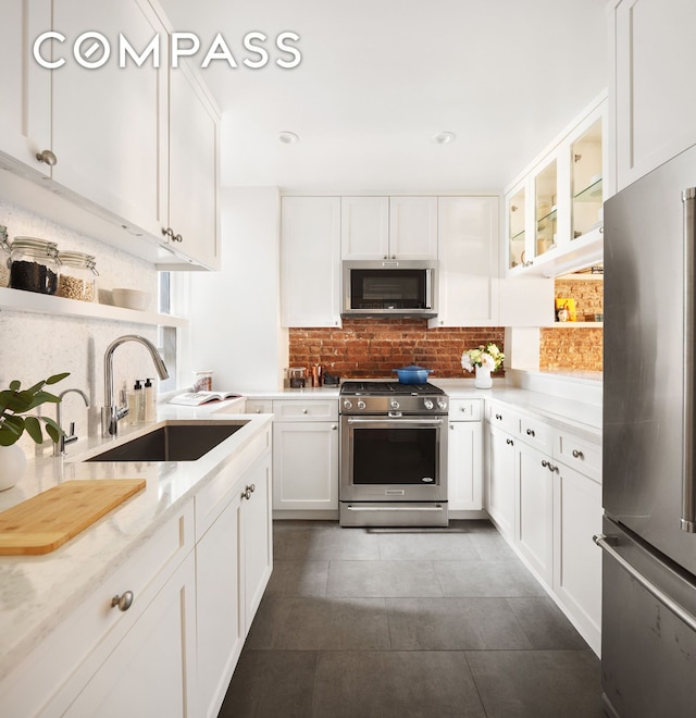 kitchen with tasteful backsplash, white cabinets, glass insert cabinets, stainless steel appliances, and a sink