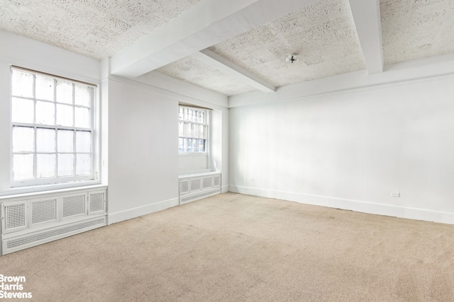 empty room featuring light colored carpet, beamed ceiling, and baseboards