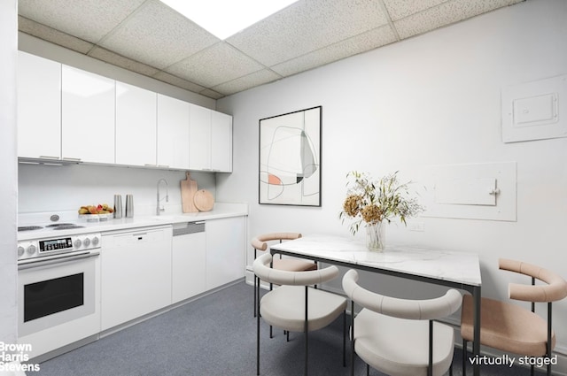 kitchen featuring wall oven, white cabinetry, light countertops, and a paneled ceiling