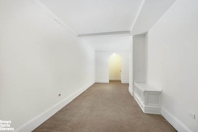 carpeted empty room featuring arched walkways and baseboards