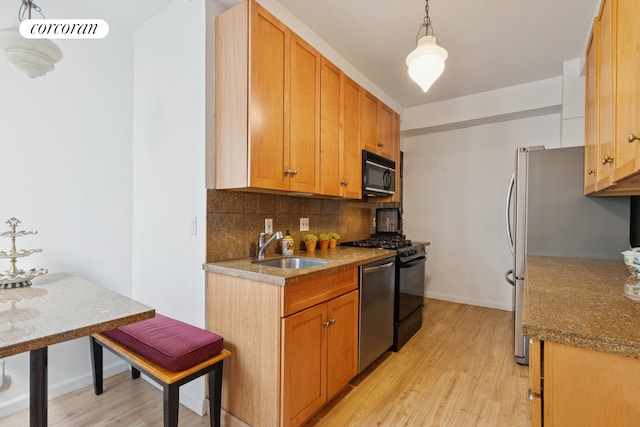 kitchen with tasteful backsplash, appliances with stainless steel finishes, light wood-style flooring, and a sink