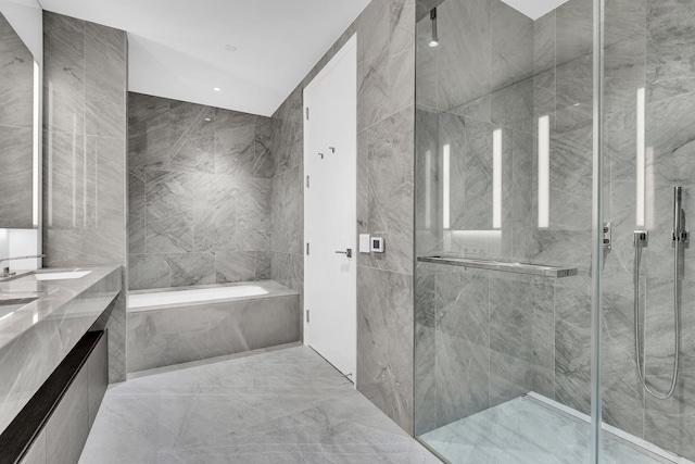bathroom featuring double vanity, a garden tub, tile walls, marble finish floor, and a marble finish shower
