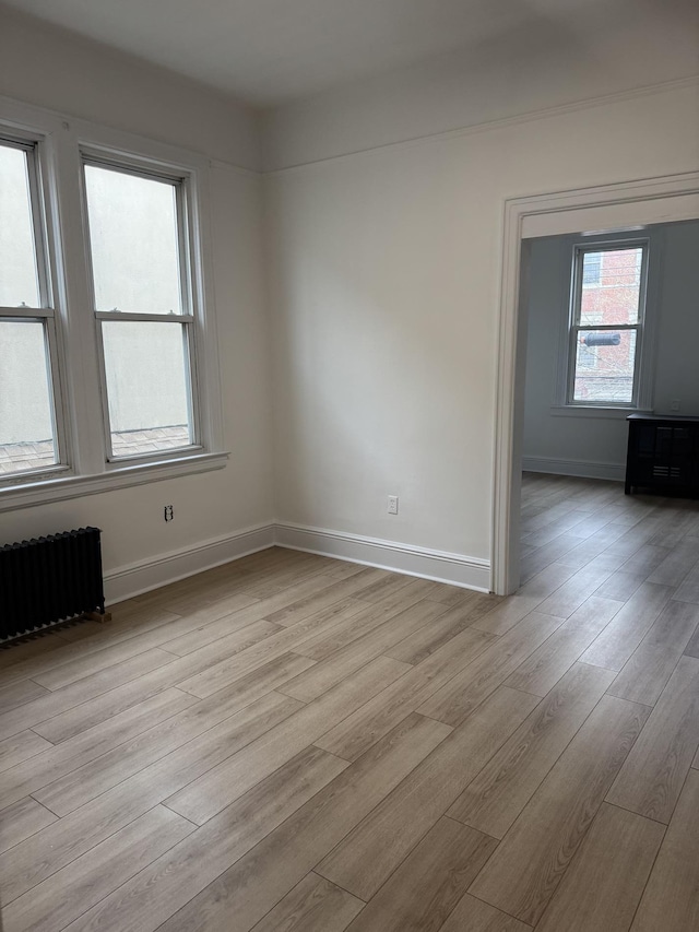 unfurnished room featuring radiator, baseboards, and wood finished floors