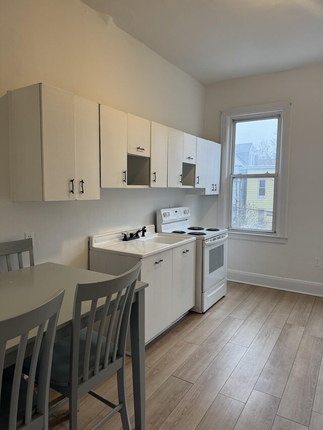 kitchen featuring light wood finished floors, baseboards, light countertops, electric range, and white cabinets