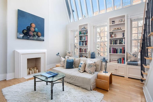 sitting room with light wood-style floors, baseboards, a wealth of natural light, and a high ceiling