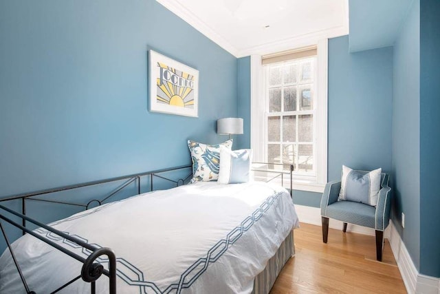bedroom with ornamental molding, wood finished floors, and baseboards