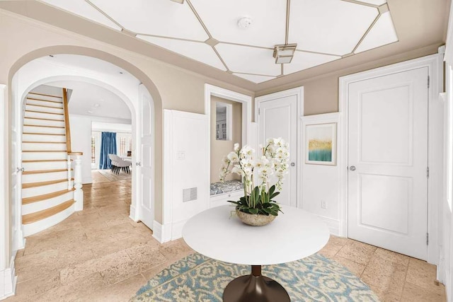 hallway featuring stone tile flooring, stairs, visible vents, baseboards, and arched walkways