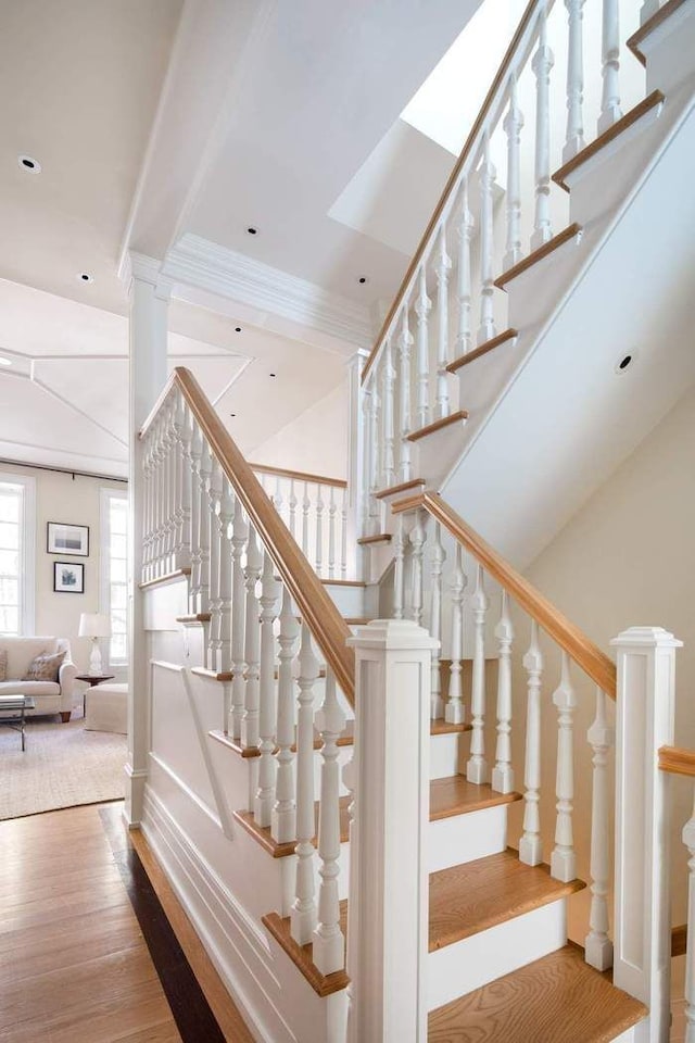 stairway featuring recessed lighting, wood finished floors, ornamental molding, and a decorative wall