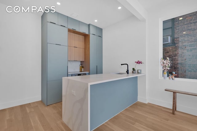 kitchen with light countertops, light wood finished floors, modern cabinets, and a peninsula