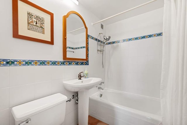 full bath featuring shower / bath combo with shower curtain, toilet, and tile walls