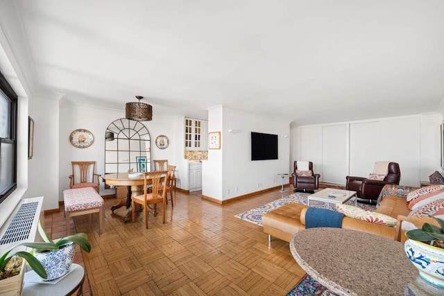 living area with baseboards, plenty of natural light, and crown molding