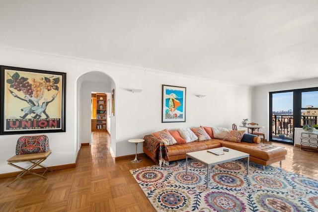 living room featuring arched walkways, crown molding, and baseboards