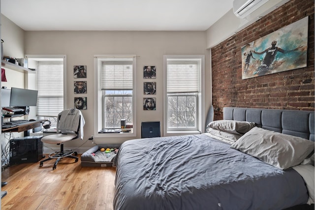 bedroom with brick wall, baseboards, and wood finished floors