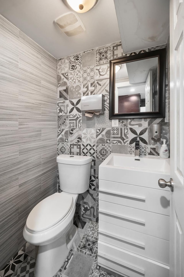 bathroom with visible vents, tile patterned flooring, vanity, toilet, and tile walls