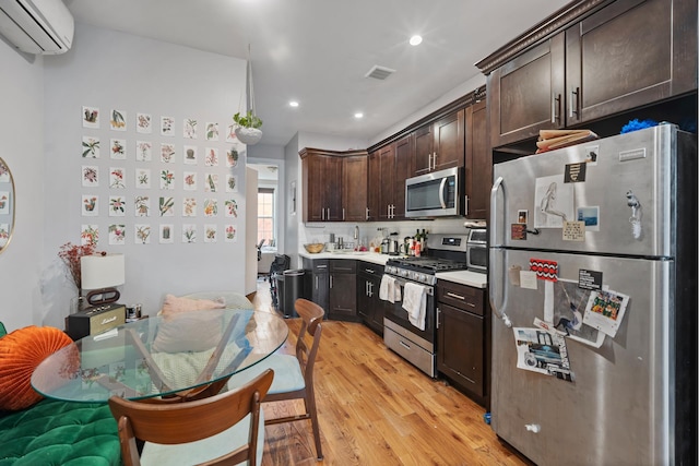 kitchen featuring dark brown cabinets, appliances with stainless steel finishes, light wood finished floors, light countertops, and a wall mounted AC