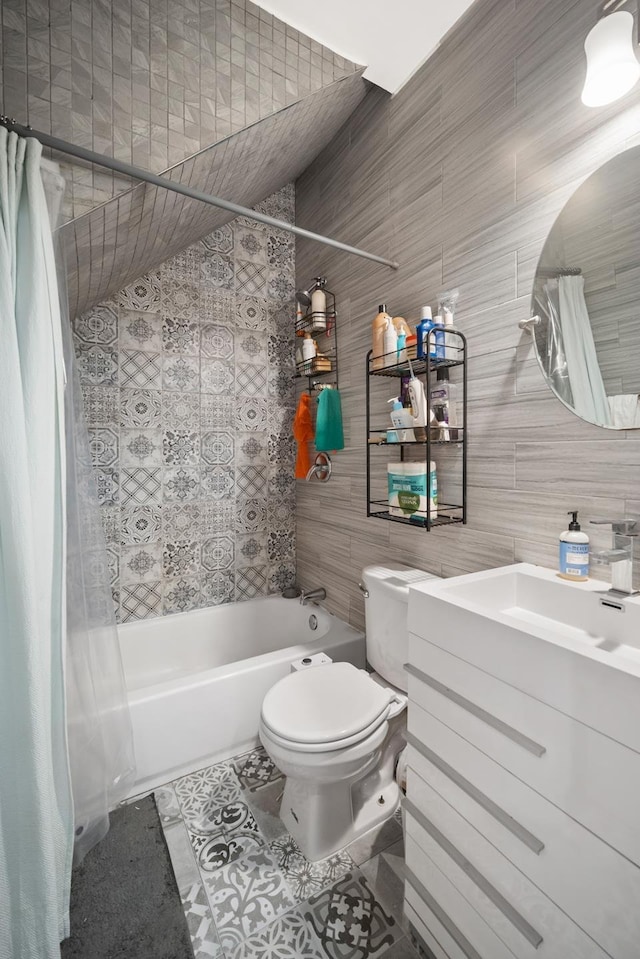 bathroom with shower / bath combo with shower curtain, vanity, tile patterned flooring, toilet, and tile walls