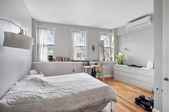 bedroom featuring an AC wall unit, baseboards, multiple windows, and wood finished floors
