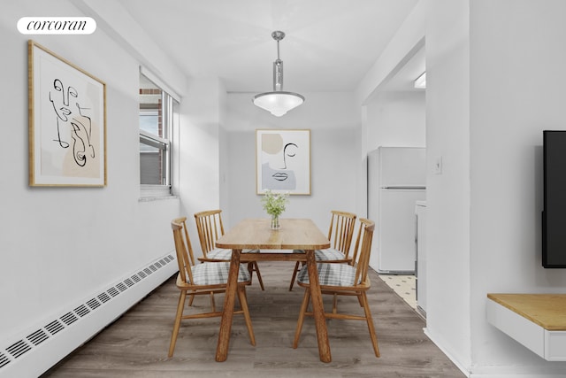 dining room featuring a baseboard heating unit, visible vents, and wood finished floors