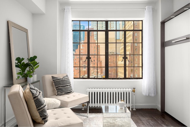 sitting room with radiator heating unit, wood finished floors, and baseboards