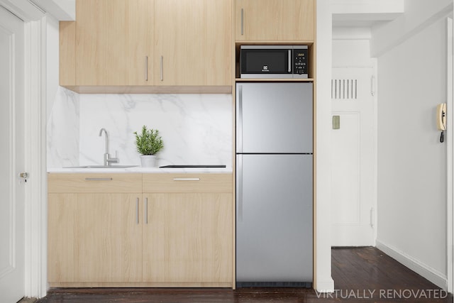 kitchen featuring light countertops, light brown cabinetry, freestanding refrigerator, a sink, and built in microwave