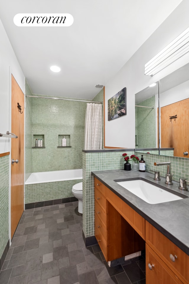 full bath featuring toilet, visible vents, tile walls, and vanity