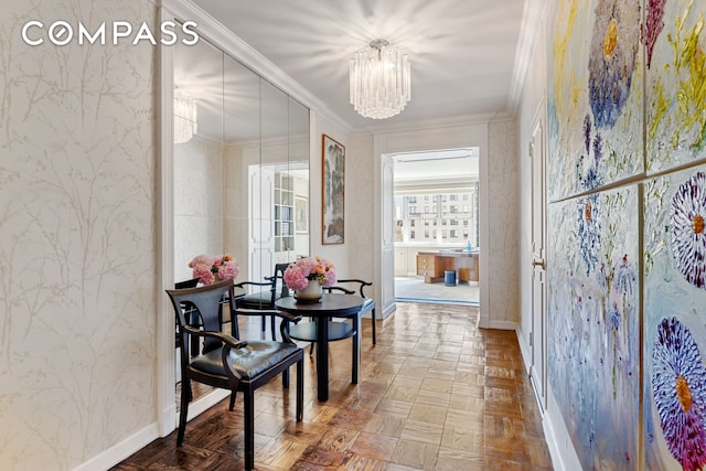 dining room featuring baseboards, ornamental molding, an inviting chandelier, and wallpapered walls