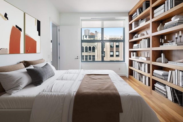 bedroom featuring a city view and wood finished floors