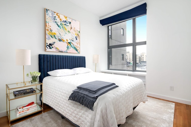 bedroom with radiator, baseboards, and wood finished floors