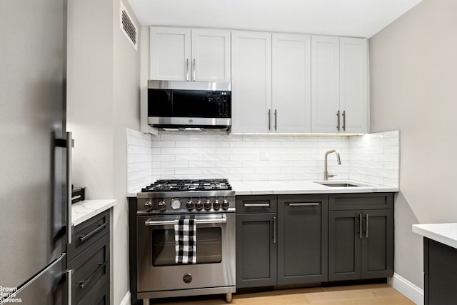 kitchen with visible vents, a sink, white cabinetry, and stainless steel appliances
