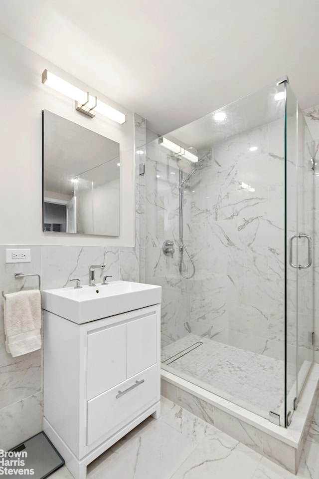 full bathroom with a marble finish shower, vanity, tile walls, and marble finish floor