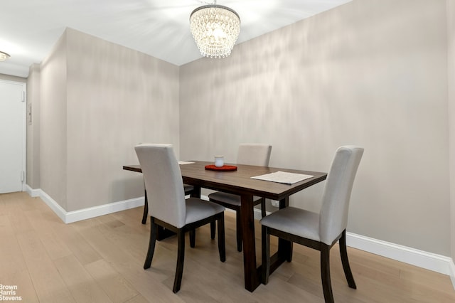 dining area featuring baseboards, light wood-style flooring, and a notable chandelier