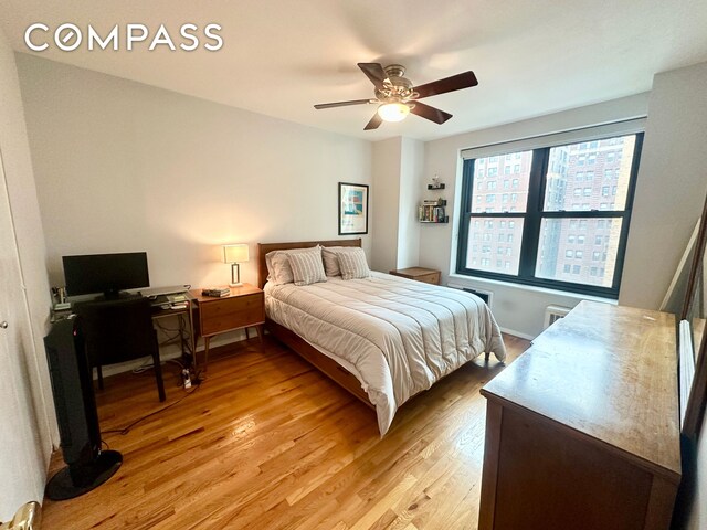 bedroom with light wood-style flooring, a ceiling fan, and baseboards