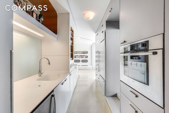 kitchen featuring a sink, stainless steel oven, white cabinets, light countertops, and modern cabinets