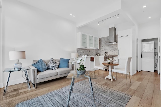 living area featuring baseboards, recessed lighting, stacked washer and clothes dryer, and light wood-style floors