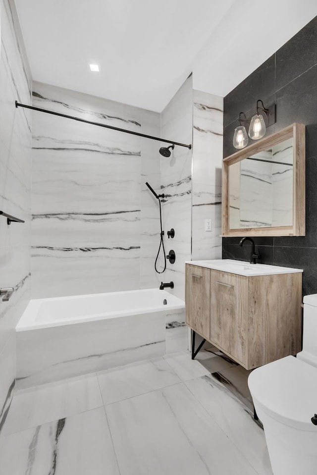 bathroom with toilet, marble finish floor, tile walls, tub / shower combination, and vanity