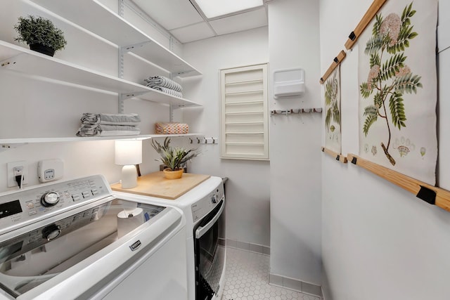 laundry area with laundry area, light tile patterned floors, baseboards, and separate washer and dryer