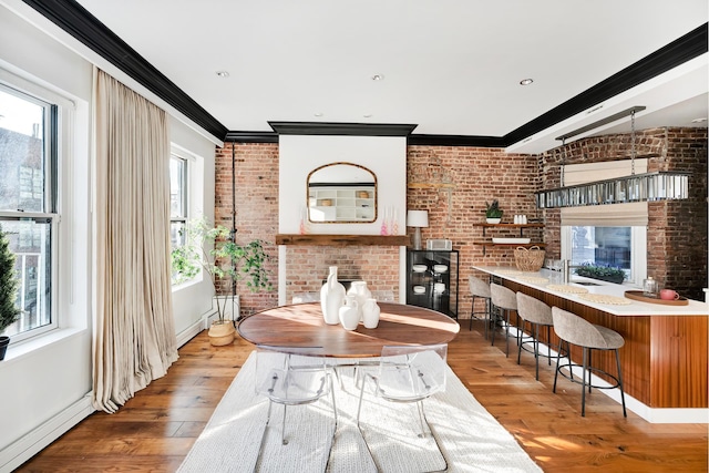 dining room with brick wall, ornamental molding, a baseboard radiator, and hardwood / wood-style flooring