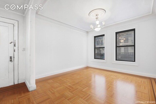 empty room with an inviting chandelier and baseboards