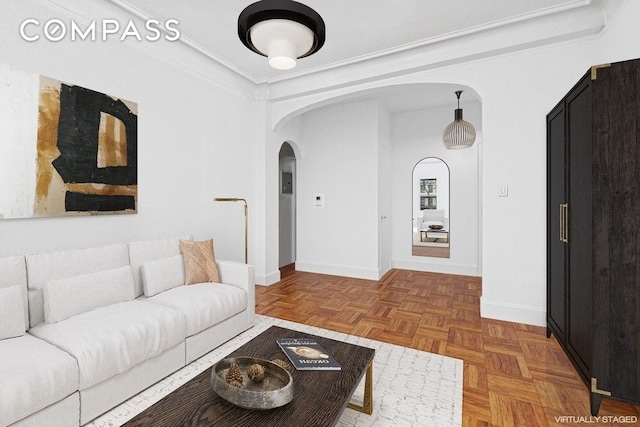 living room featuring baseboards, arched walkways, and crown molding